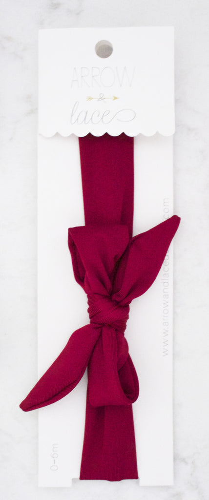 Burgundy headband with a bow on a white background