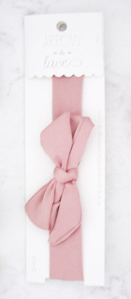 Pink hair bow on a white card with  branding.
