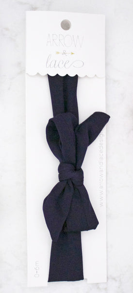 Navy blue bow headband on a white background