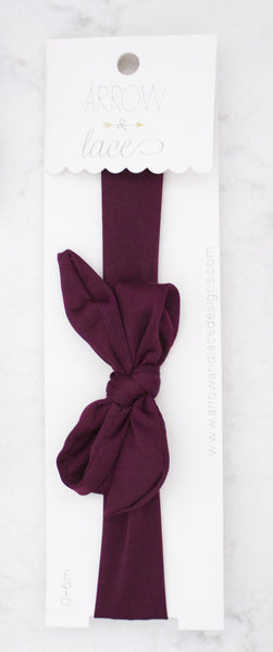 Maroon headband with a bow on a white background